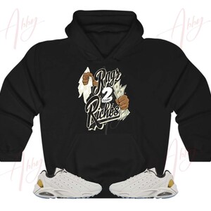 May include: Black hoodie with a graphic print of a hand holding money and the text "Rags 2 Riches". White sneakers with gold accents.