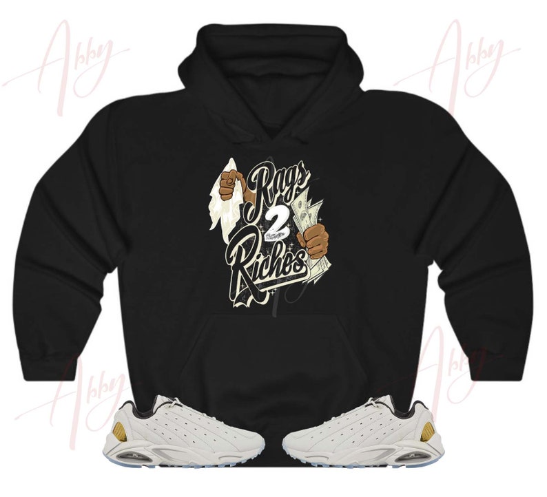 May include: Black hoodie with a graphic print of a hand holding money and the text "Rags 2 Riches". White sneakers with gold accents.