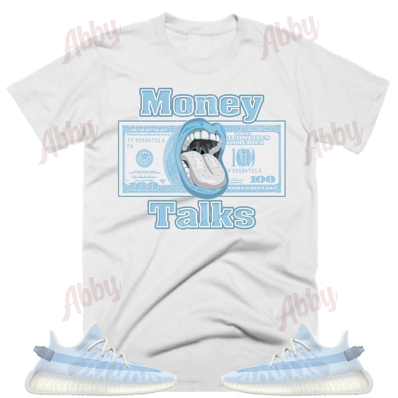 May include: A white t-shirt with a blue dollar bill graphic featuring a mouth with a tongue sticking out. The text "Money Talks" is printed below the graphic. A pair of light blue and white sneakers are shown below the t-shirt.