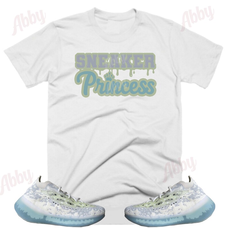 May include: White t-shirt with the text "Sneaker Princess" in blue and green lettering. A pair of white and light green sneakers with a blue translucent sole.