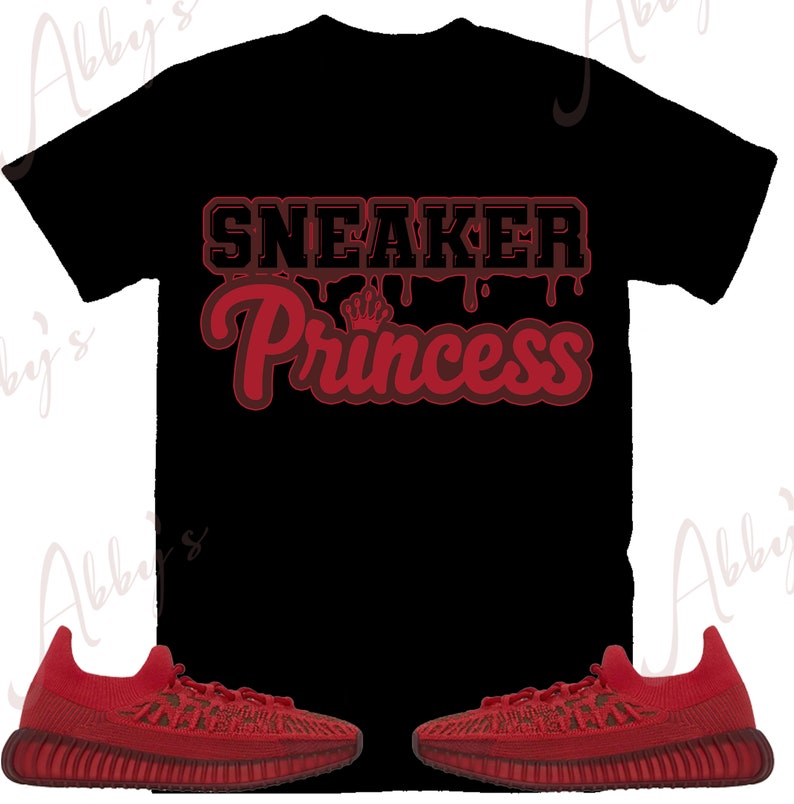 Peut inclure: T-shirt noir avec le texte "SNEAKER Princess" en rouge et un petit motif de couronne. Deux baskets rouges sont en bas de l'image. Les baskets ont un design textur&eacute;.