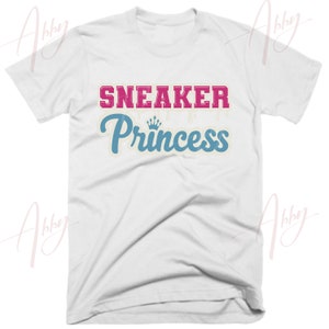 May include: White t-shirt with the text "SNEAKER Princess" in pink and blue with a crown graphic.