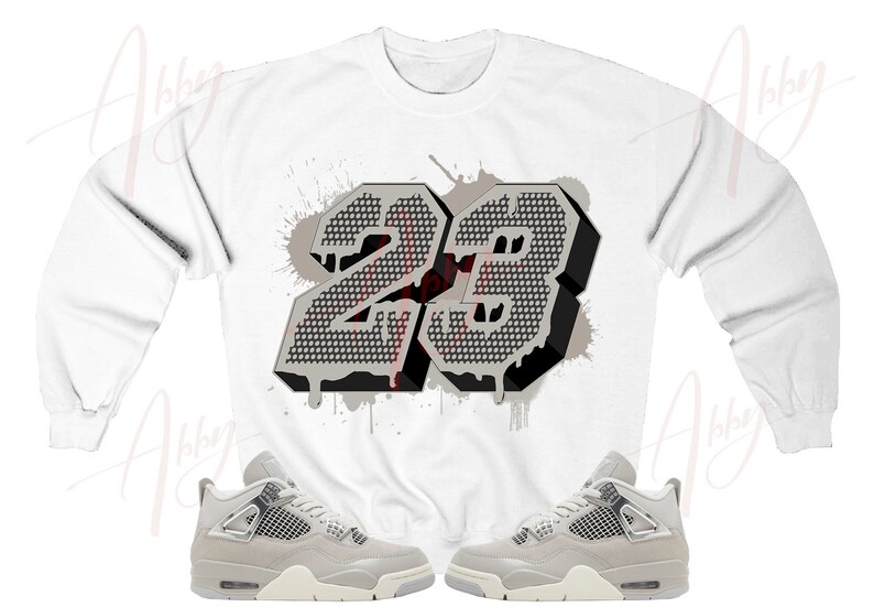 May include: White long-sleeve sweatshirt with a gray and black number "23" graphic. The number is in a 3D style with a dripping paint effect. Two pairs of gray and white sneakers are shown below the sweatshirt.