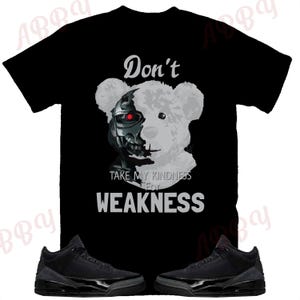 May include: Black t-shirt with a graphic of a robot bear with the text "Don't Take My Kindness For Weakness".  The t-shirt is paired with black sneakers.