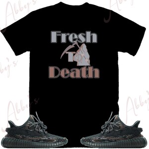 May include: Black t-shirt with the text "Fresh to Death" in grey and brown lettering. The text is accompanied by a graphic of a skeleton holding a scythe. A pair of black and green camouflage sneakers are also pictured.