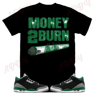 May include: Black t-shirt with green text that reads "MONEY 2 BURN" and a green and white dollar bill rolled into a cigarette shape.  A pair of black and green sneakers with white soles.