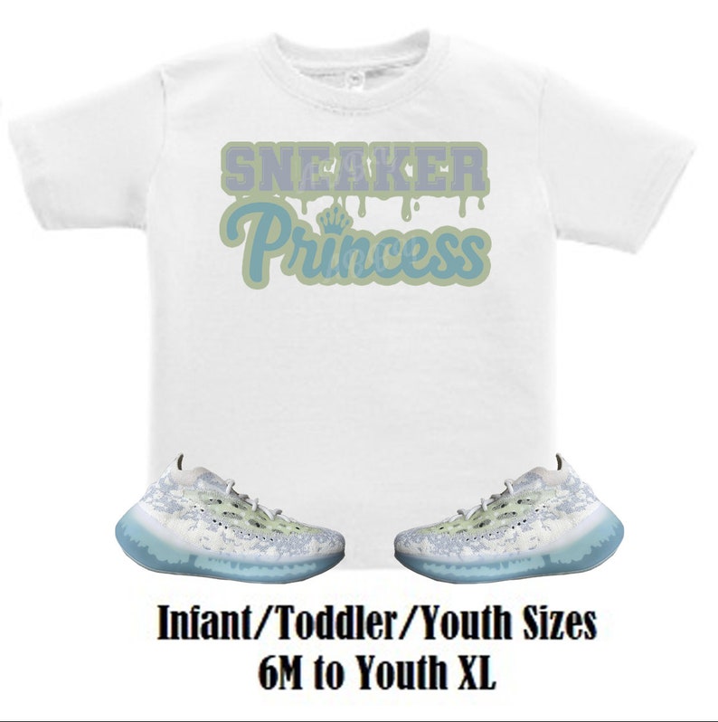 May include: White t-shirt with the text "Sneaker Princess" in blue and green dripping letters. Two pairs of white and light blue sneakers with a speckled pattern.