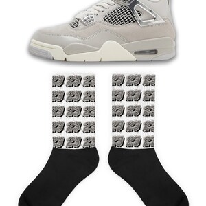 May include: A pair of grey and white sneakers with black socks featuring a repeated pattern of the number 23.