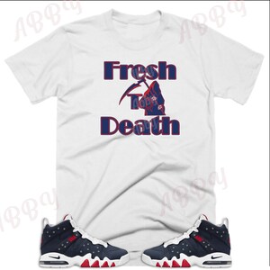 May include: White t-shirt with the text "Fresh To Death" in blue and red lettering, featuring a reaper graphic. A pair of navy blue and red sneakers with white accents.