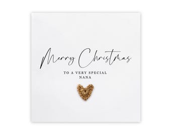 May include: A white card with black text that reads "Merry Christmas to a very special Nana". A gold glitter heart is in the center of the card.