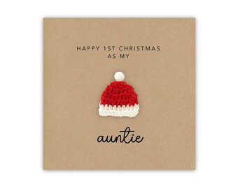 May include: A brown card with the text "Happy 1st Christmas as my auntie" and a small red and white crocheted Santa hat.