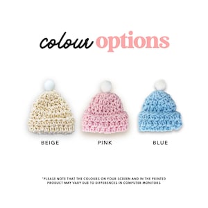 May include: Three crocheted hats in beige, pink, and blue with white pom-poms. The hats are displayed on a white background with the text "colour options" above them and the color names below each hat.