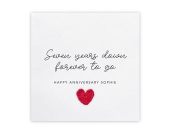 Peut inclure: Une carte blanche avec le texte "Seven years down forever to go" et "Happy Anniversary Sophie". Un petit cœur rouge se trouve en bas au centre de la carte.
