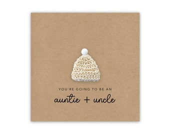 May include: A brown card with a small crocheted hat with a white pom-pom on top. The card says "You're going to be an auntie + uncle".