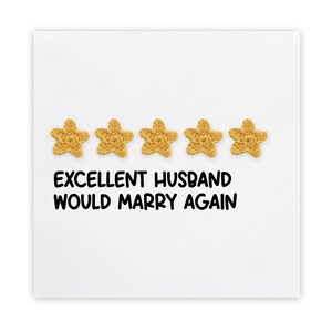 Op de afbeelding: Een witte kaart met vijf gouden sterren en de tekst "EXCELLENT HUSBAND WOULD MARRY AGAIN" in het zwart. De sterren zijn in een rij boven de tekst geplaatst.