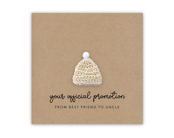 May include: A card with a small knitted baby hat on a brown background. The card says "your official promotion from best friend to uncle".