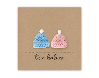 May include: A brown card with a blue and pink crocheted baby hat on each side. The card says "Congratulations on the birth of your twin babies".