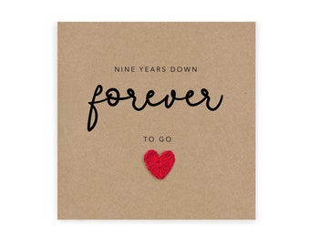 Peut inclure: Une carte marron avec le texte "NINE YEARS DOWN forever TO GO" et un cœur rouge en crochet.
