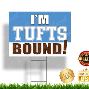 May include: A blue and brown yard sign with the text "I'M TUFTS BOUND!" in white lettering. The sign is on a metal stake and has a "FREE STAKES" and "MADE IN USA" sticker.