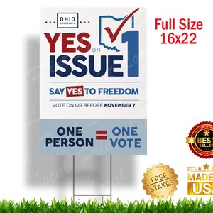 May include: A blue and red yard sign with the text "YES ON ISSUE 1" and "SAY YES TO FREEDOM". The sign also includes a checkmark in a circle and the text "ONE PERSON = ONE VOTE".