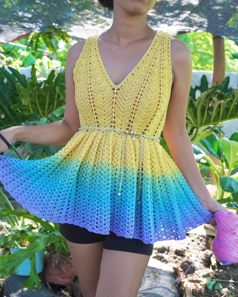 May include: A crochet top with a rainbow ombre design. The top is sleeveless and has a V-neck. The top is made with a delicate crochet stitch and has a flowing, feminine silhouette.