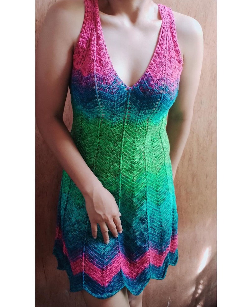 May include: A sleeveless crochet dress with a V-neckline and a gradient pattern of pink, green and blue.