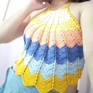 Op de afbeelding: Een handgemaakte, veelkleurige gehaakte haltertop. De top heeft een chevronpatroon in tinten geel, perzik, blauw en wit. De top is een zomerkledingstuk, perfect voor warm weer. De top is een uniek, handgemaakt stuk.