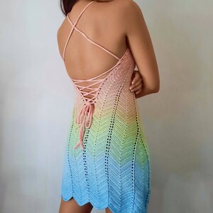 May include: A rainbow ombre crochet dress with a lace-up back. The dress is sleeveless and has a fitted bodice.