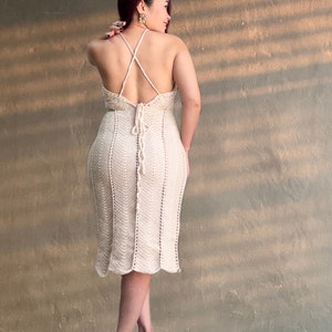 May include: A white crochet dress with a criss-cross back and a tie at the waist.