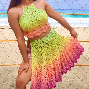 May include: A handmade crochet two-piece set in a gradient of colors, transitioning from yellow-green to coral and ending in a vibrant pink. The halter top and skirt feature a scalloped edge, perfect for beachwear or summer events.