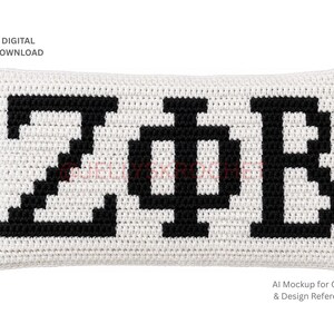 May include: A rectangular crochet cushion featuring a white background with the black Greek letters Zeta, Phi, and Beta stitched in a pixelated style. The image includes the text Digital Download and AI Mockup for Color & Design Reference.