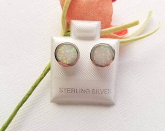 May include: A pair of white opal stud earrings on a white card with the text "STERLING SILVER".