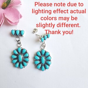 May include: A pair of dangle earrings with turquoise stones set in silver. The earrings feature a cluster of turquoise stones in the shape of a flower. The earrings are approximately 3.8 cm long.