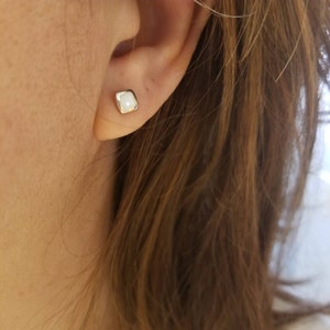 May include: A pair of silver square stud earrings with white opal stones.
