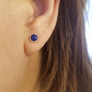 May include: A pair of silver stud earrings with a round blue gemstone.