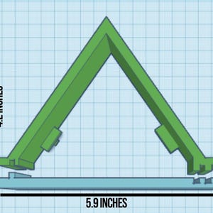 Puede incluir: Un soporte triangular de plástico verde con una base plana, que mide 15 cm de ancho y 10,7 cm de alto. El soporte está diseñado para sostener un teléfono o una tableta en posición vertical.