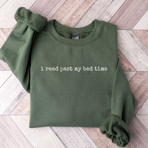 Puede incluir: Una sudadera verde con el texto "i read past my bed time" en blanco.