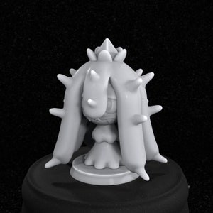 May include: A gray 3D printed figurine of a Pokemon character with spiky hair and a long, flowing dress. The figurine is standing on a round base.