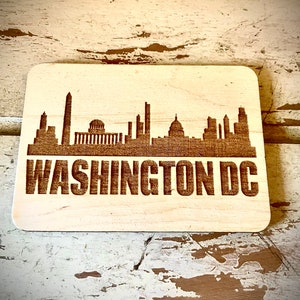 May include: A wooden sign with a laser-engraved silhouette of the Washington, D.C. skyline. The text "WASHINGTON DC" is also engraved below the skyline.
