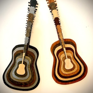 May include: Two wooden acoustic guitars with layered wood designs in different shades of brown and gray. The guitars are layered in a concentric circle pattern, creating a unique and artistic look.