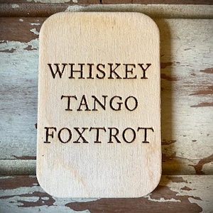May include: A wooden sign with the words "Whiskey Tango Foxtrot" engraved on it.