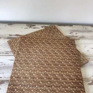 May include: Three wooden coasters with a geometric pattern. The coasters are made of light brown wood and have a dark brown geometric pattern.