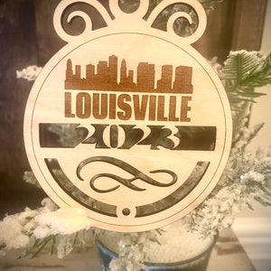Ornament - Louisville Skyline cityscape. 4&quot; X 4.75&quot; wood ornament with choice of year.  Great souvenir or memento from your favorite city.
