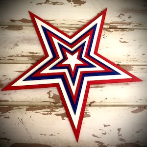 May include: A layered paper star in red, white, and blue, reminiscent of the American flag. The star is made of multiple layers of paper, creating a three-dimensional effect.