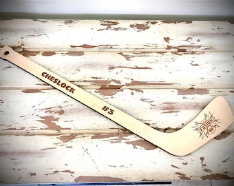 May include: A wooden hockey stick with the name "CHESLOCK #3" and the word "FUSION" with a lightning bolt design engraved on the blade.