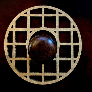 May include: A round, gold-colored metal knob with a grid pattern. The knob has a dark brown wooden center.