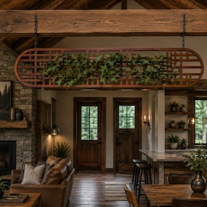 May include: A rectangular wooden lattice screen with rounded ends, suspended from a ceiling beam by two black chains. The grid-like structure is filled with green ivy foliage, creating a decorative partition between the living and kitchen areas.