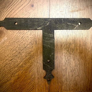May include: A dark green metal T-shaped bracket with decorative pointed ends. The bracket has two holes on the top and one hole on the bottom.