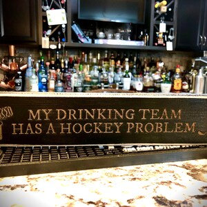 Letrero de barra divertido: Mi equipo de bebedores tiene un problema de hockey