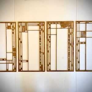 Op de afbeelding: Vier houten frames met geometrische ontwerpen, elk met een ander patroon. De frames zijn allemaal even groot en zijn in een rij gerangschikt.